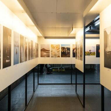 A well-lit art exhibition featuring diverse photographic prints in a modern indoor gallery.