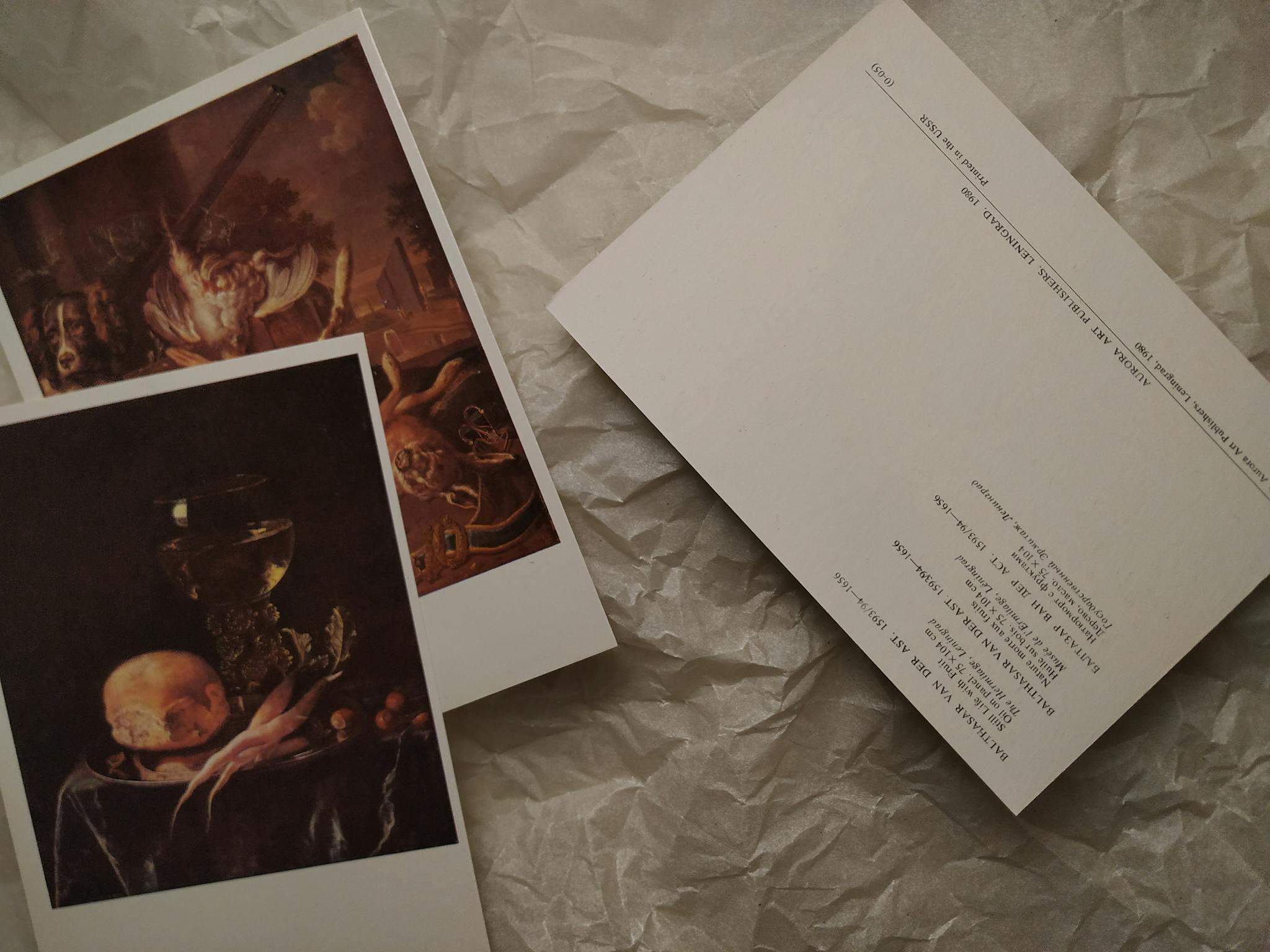 Two vintage art postcards on a textured crumpled paper surface, showcasing classic paintings.